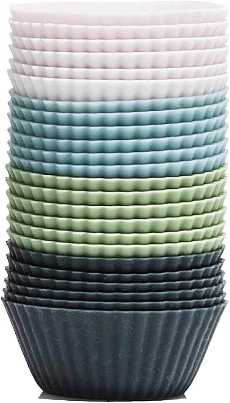 The Silicone Kitchen Mini Baking Cups in four colors arranged on a baking sheet