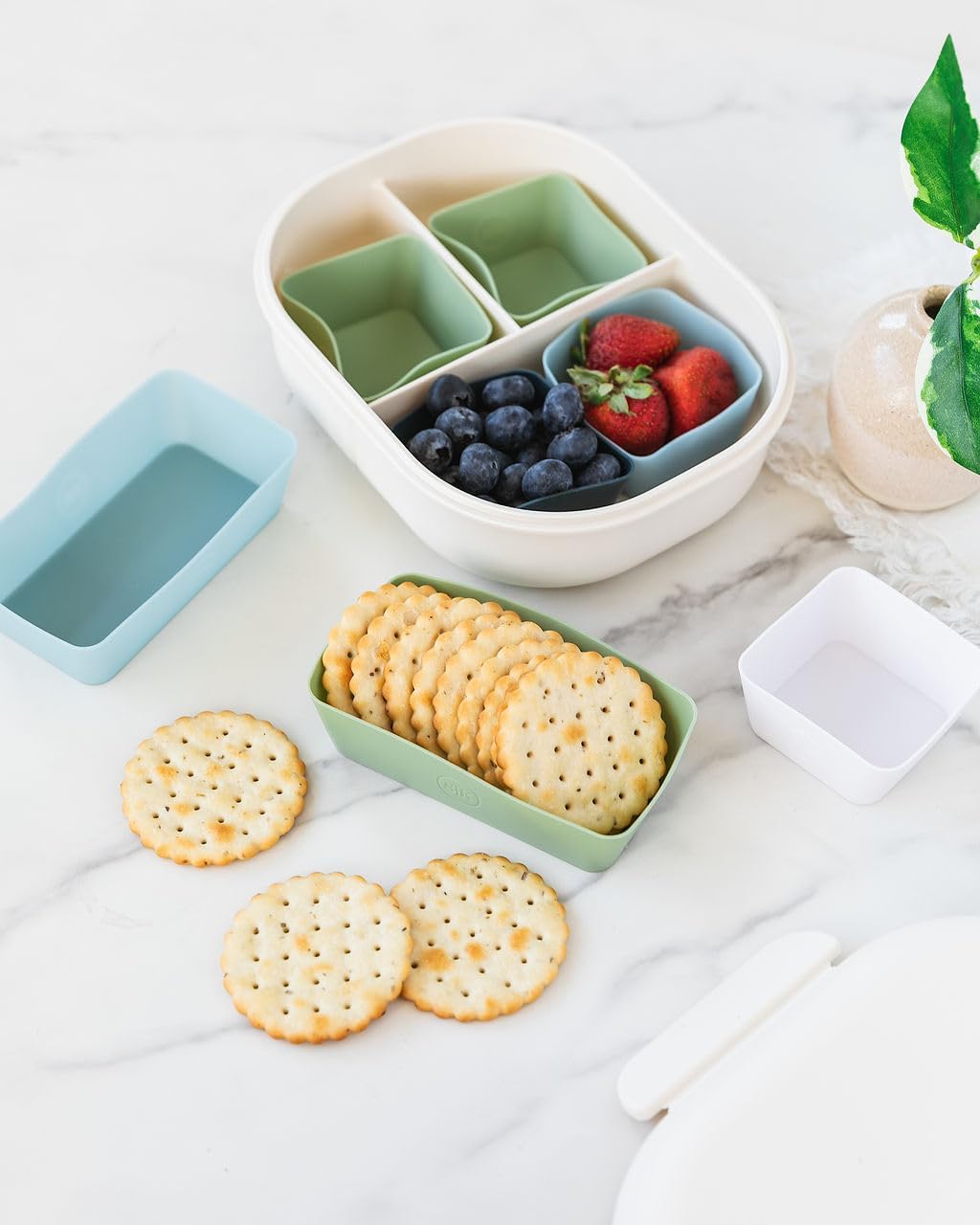 Silicone Kitchen Bento Cups arranged on a wooden cutting board with fresh vegetables and a baking sheet in the background